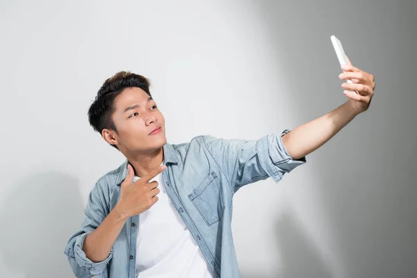 Studio Strzał Uśmiechnięty Azjatycki Młody Człowiek Robi Selfie Smartfonem Stojąc — Zdjęcie stockowe