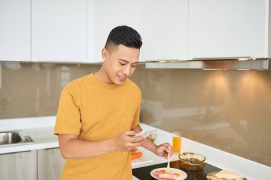 Cep telefonu tutan kahvaltı mutfak, otururken yakışıklı genç