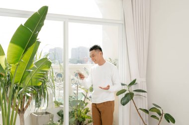 Genç Asyalı adam akıllı telefon kullanıyor.