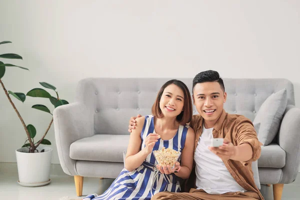 Shot of a cheeful young Asian couple watching television at home