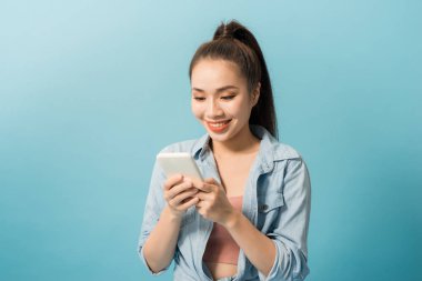 Mavi arka plan üzerinde cep telefonu tutan neşeli bir rahat kız Portresi