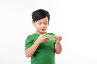 Zeki çocuk beyaz arka planda izole edilmiş yeşil akıllı cep telefonuyla oynuyor.