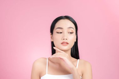 Güzel genç Asyalı kız pembe torbaya mükemmel tenine dokunuyor