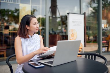 Güzel bir kadın kentteki bir kafede oturup kitap okuyor, tatilinin tadını çıkarıyor ve kahve içiyor.