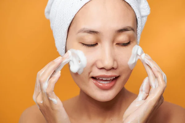 Jemná polonahá žena zabalená v ručníku mytí obličeje s f — Stock fotografie