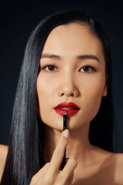 Güzel kadın dudaklarına ruj ile boyar. Güzel bir kadın yüzü. Makyaj ayrıntı. Güzellik kız mükemmel deri ile.