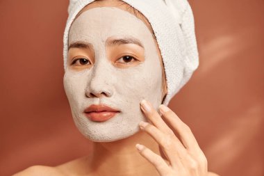 Yüzünde kil maske olan genç ve güzel bir kadın. Salon cilt bakımı, doğal yosun kremi.. 