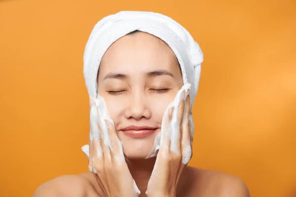 Hermosa Chica Asiática Poniendo Crema Cara Aislado Sobre Fondo Naranja — Foto de Stock