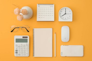 Not defteri, fare, telefon, hesap makinesi, gözlük, kalem, takvim, turuncu zemin alarmı. Flatlay, üst görünüm.