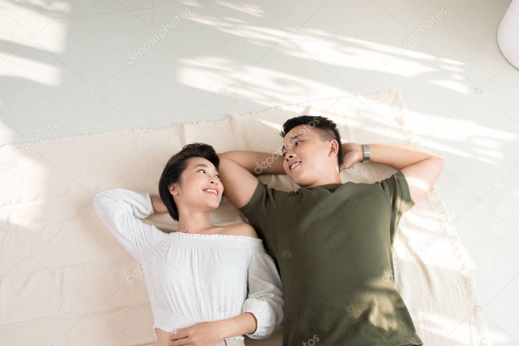 Young happy loving Asian couple boyfriend and girlfriend lying on the floor.