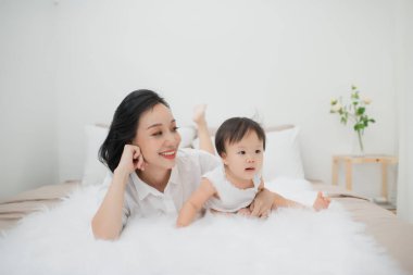 Genç anne kızıyla evde yatakta oynuyor.