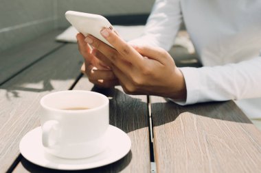 Kahve dükkanında ahşap masa üzerinde cep telefonu kullanarak kadın el