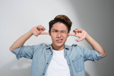 Sinirli genç duygusal adam, kulaklarını elleriyle tıkamış, izole edilmiş beyaz arka plan.. 