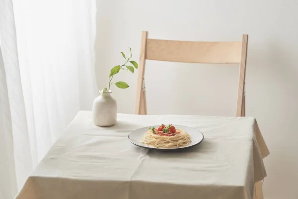 handmade pasta with ragout sauce on plate on vintage white table with colander and flowers