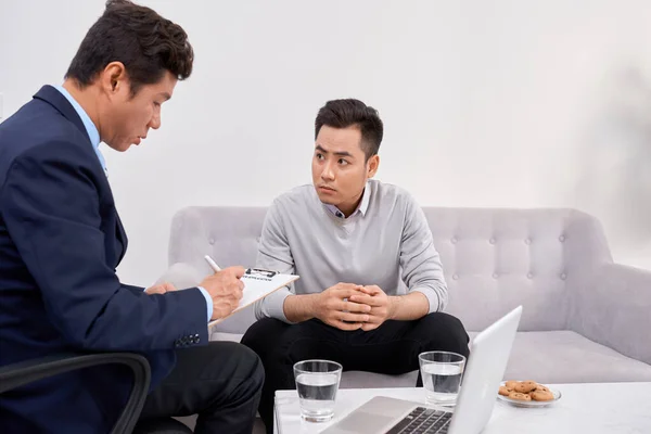 Listen to me. Asian man wrinkling forehead while looking at his therapist