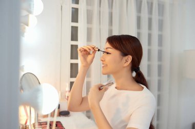 Güzel Asyalı kadın kirpikleri için rimel sürüyor.