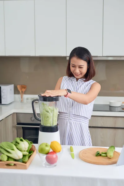 家庭のキッチンでジュースマシンで緑のジュースを作る美しいアジアの女性のジュース 健康的なコンセプト — ストック写真