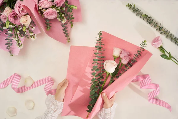 Making pink flowers bouquets with scissor on white background. Holiday, mothers day, valentine day concept. Top view, flatlay