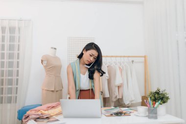 Moda trendlerini tartışıyoruz. Güzel genç kadın cep telefonu konuşuyor ve onu atölye ayakta iken dizüstü bilgisayar üzerinde çalışıyor