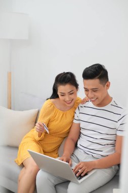 Dizüstü bilgisayar ile kanepede oturan mutlu genç Çift