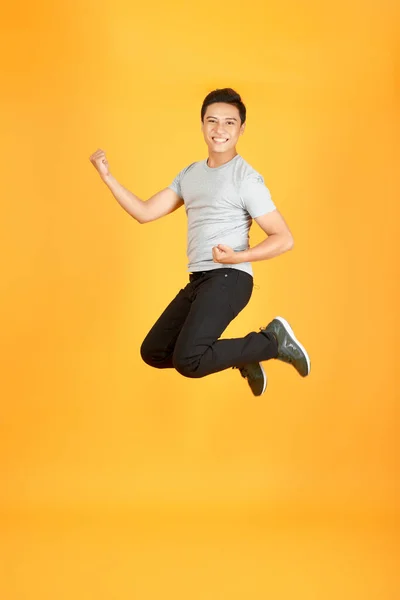 주황색 성공을 축하하면서 티셔츠 점프를하는 남자의 초상화 — 스톡 사진