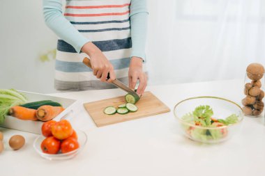 Genç kadın mutfakta sebze kesiyor. Kadın sağlıklı gıda pişirme. 