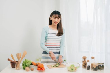 Genç kadın mutfakta sebze kesiyor. Kadın sağlıklı gıda pişirme. 