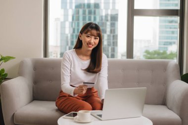 Loft dairedizüstü bilgisayar kullanarak kredi kartı ile genç kadın