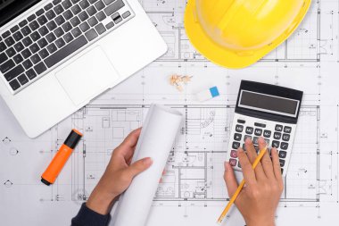 Sarı kask ve çizim araçları ile inşaat planları planları üzerinde teslim