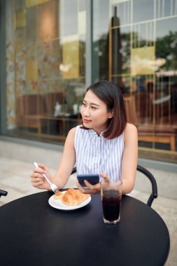 Kafede akıllı telefon kullanan Asyalı bir kadın.