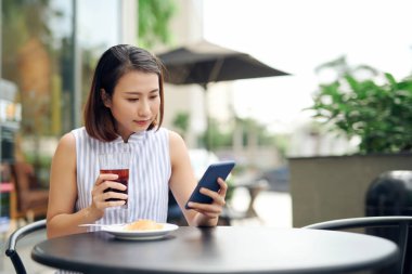 Kafede akıllı telefon kullanan Asyalı bir kadın.