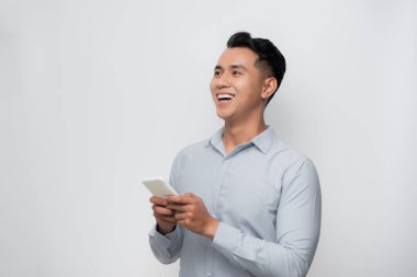 Yakışıklı Asyalı genç adam akıllı telefon kullanıyor.