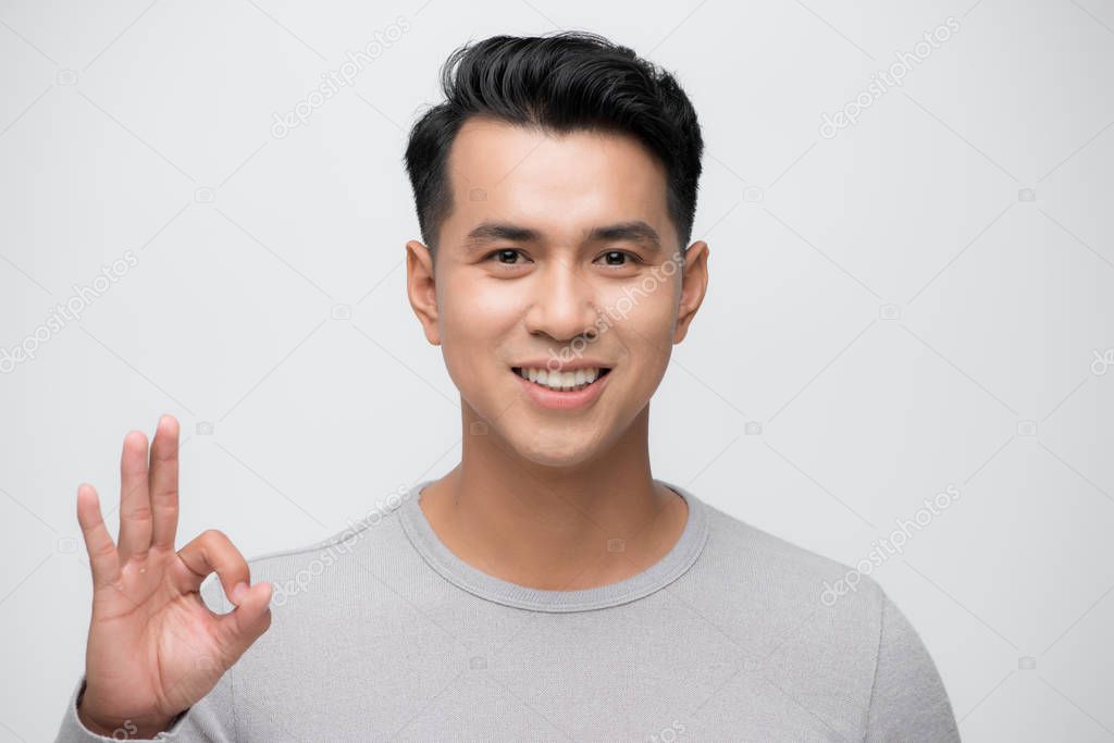 portrait of an asian man doing the okay gesture