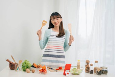 Güzel genç asyalı kadın yemek tarifi okuma veya salata yaparken göstermek izlerken