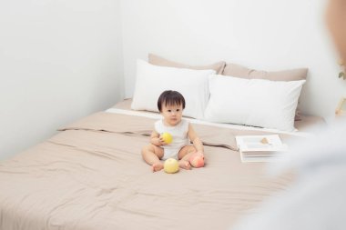 Yatakta oyuncakla oynayan tatlı bir bebek. Çocuk evde oynuyor.