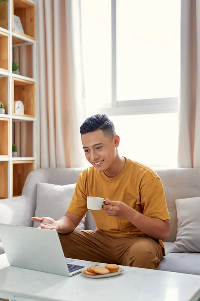 Glücklicher Junger Mann Sitzt Auf Sofa Und Benutzt Laptop — Stockfoto