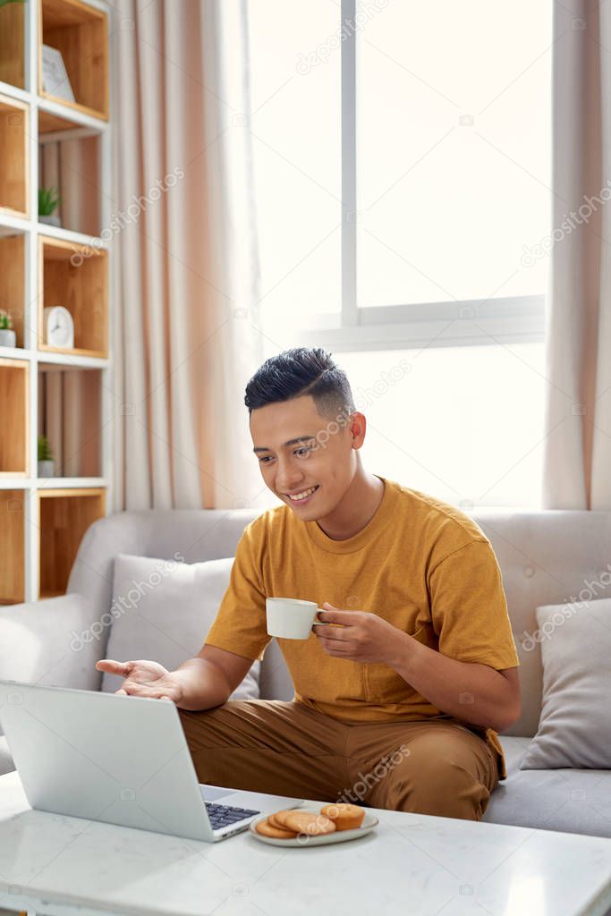 happy young Man sitting in sofa and using laptop