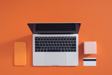 Bilgisayarı, masası, alışveriş çantaları, kredi kartları, kuponları ve ürünleri olan çevrimiçi alışveriş konsepti