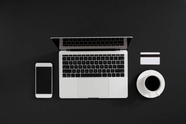 Modern dizüstü bilgisayar, akıllı telefon, kahve ve kredi kartı ile çalışma alanının düz yatay fotoğrafı, renk arkaplanı.