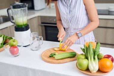 Evdeki mutfakta meyve püresi yapmak için sebze kesen bir kadın. Sağlıklı konsept.
