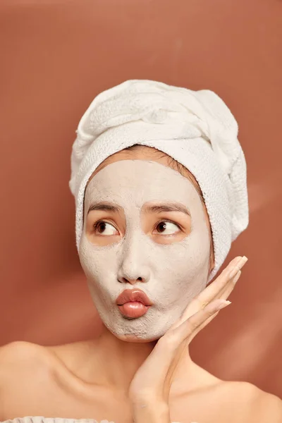 水疗少女满脸喜色 脸上涂粘土面罩 接受美容疗法 头上戴白色软巾 — 图库照片