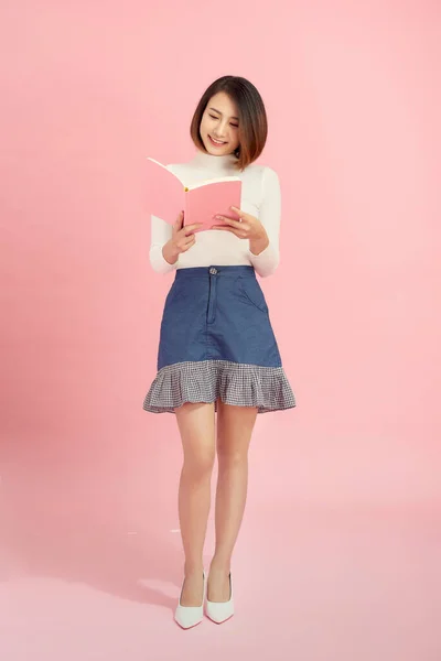 Mladá Asijská Dívka Stojící Čtení Interdting Kniha Izolované Růžovém Pozadí — Stock fotografie