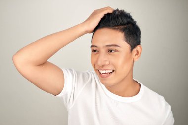 Saçlarına dokunan yakışıklı kendine güvenen Asyalı adamın yakın portresi