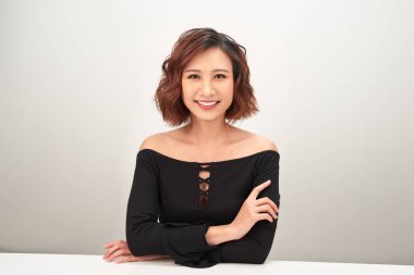 Masada oturan genç bir kadın, beyaz arka planda izole edilmiş.