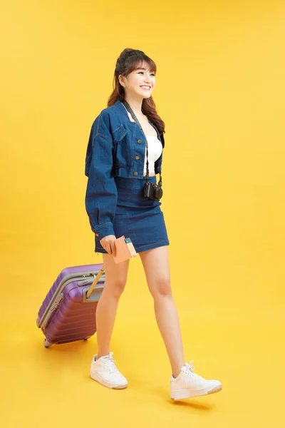 夏のカジュアル服の若い観光客の女の子 紫のスーツケースと パスポート 黄色の背景に隔離されたチケット — ストック写真
