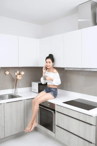 Sexy Azji Lady Siedzi Kuchnia Podczas Rozmowy Przez Telefon Trzymając — Zdjęcie stockowe