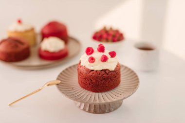 Beyaz arka plan üzerinde çeşitli muffins bir tabak ile standında Ahududu cupcake