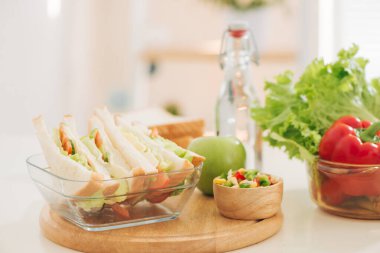 Parlak mutfaktaki masanın üzerindeki kesme tahtasının üzerinde sandviç. - Öğle yemeği. Marullu sandviç istiyorum. Sağlıklı yeme kavramı.