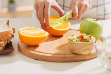 Kadın kollarının yakın çekimleri turuncuyu bıçakla dilimlere ayırıyor..