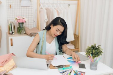 Genç bir Asyalı moda tasarımcısı atölyesinde çalışıyor.